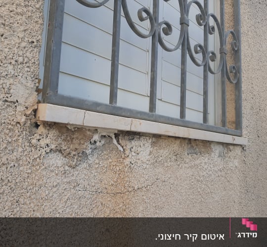 נזקי רטיבות וסדקים בקיר חיצוני מתחת לאדן חלון